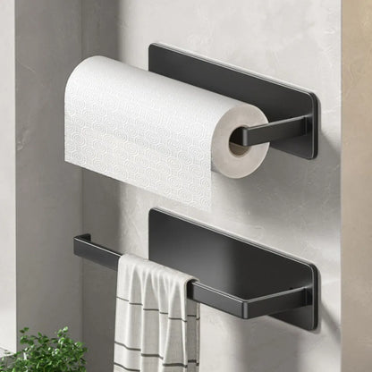 Black wall-mounted paper towel holder with a roll of paper towels and a towel on a light gray wall.